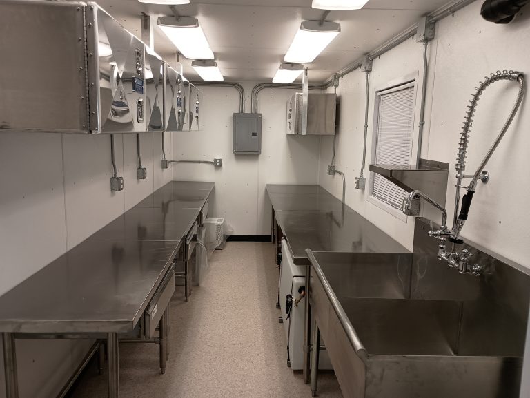 Stainless steel kitchen interior inside a custom shipping container, designed for remote work camps and industrial food service operations in Alaska